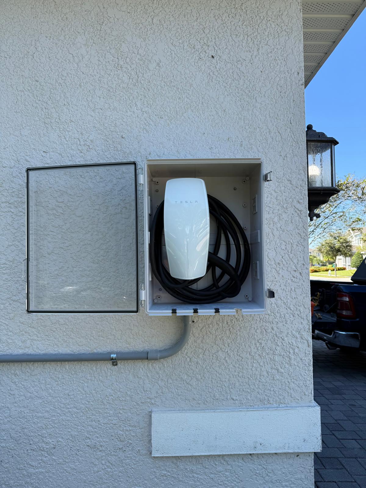 Tesla Universal Wall Connector installed inside a weather-resistant outdoor enclosure at a vacation rental